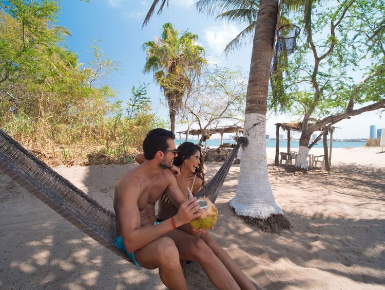 Imagínate estar en una hermosa isla con playa de aguas turquesas, mientras te comes un coco en una hamaca