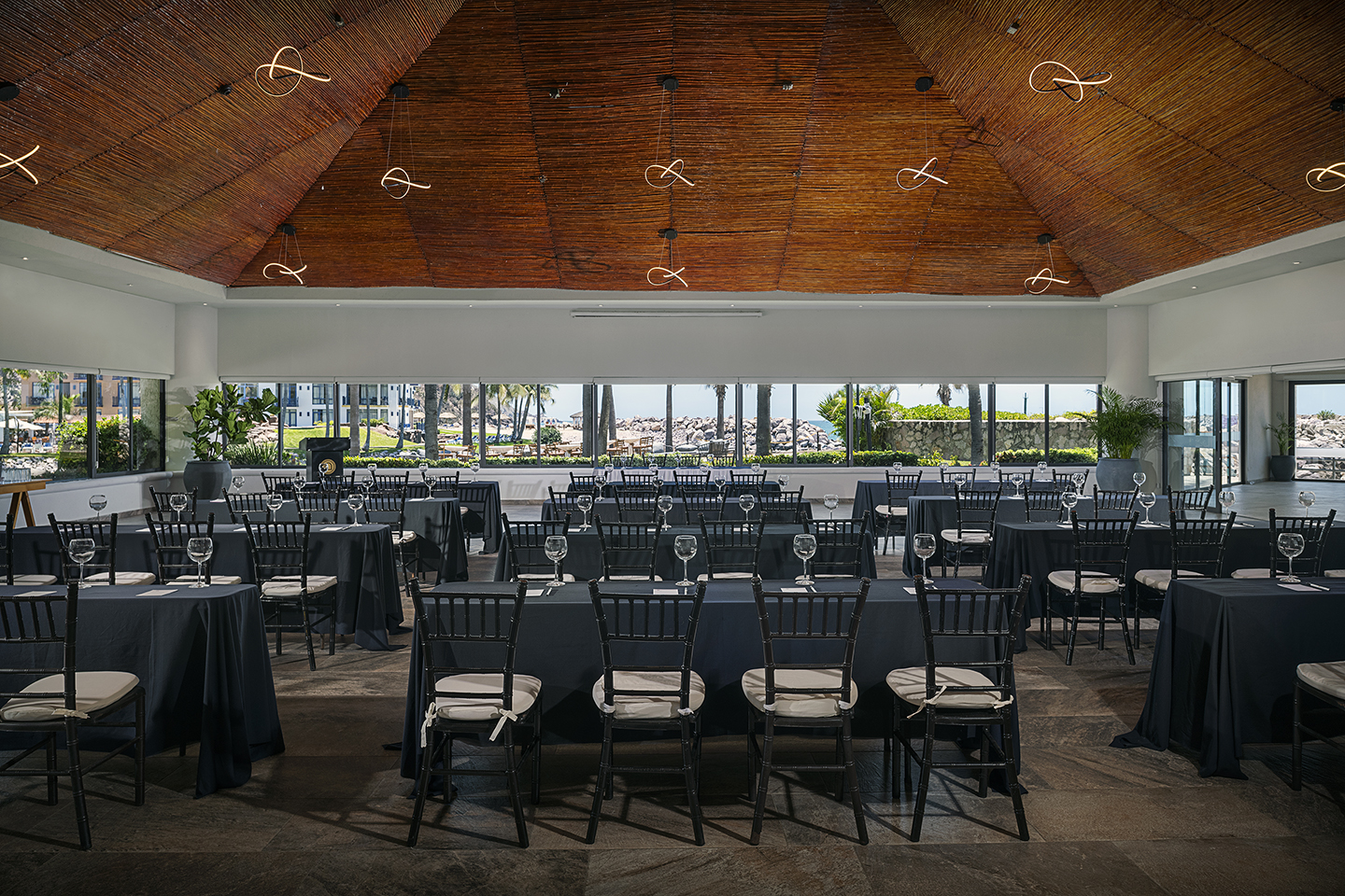 Indoor event venue with banquet tables and ocean views.