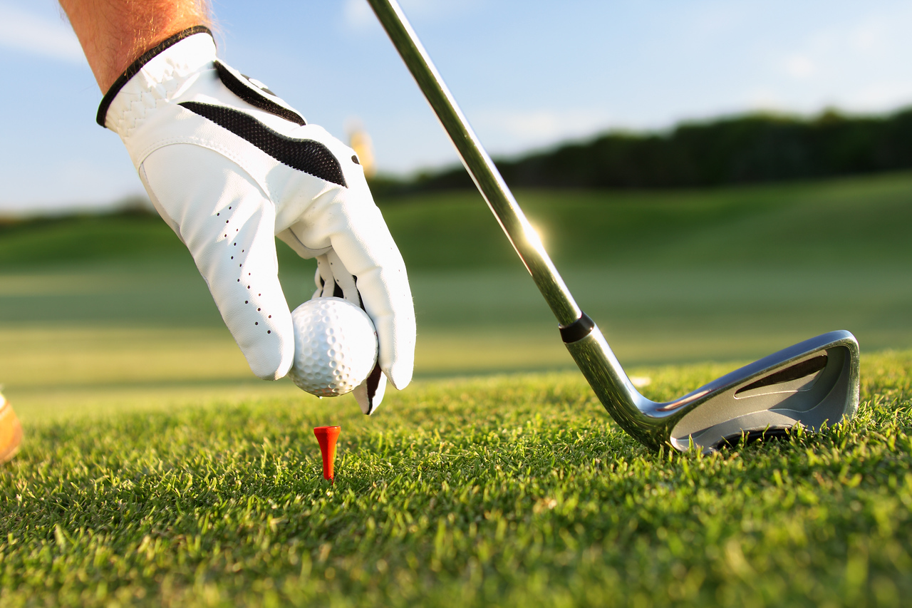 Three golfers smile while holding golf clubs