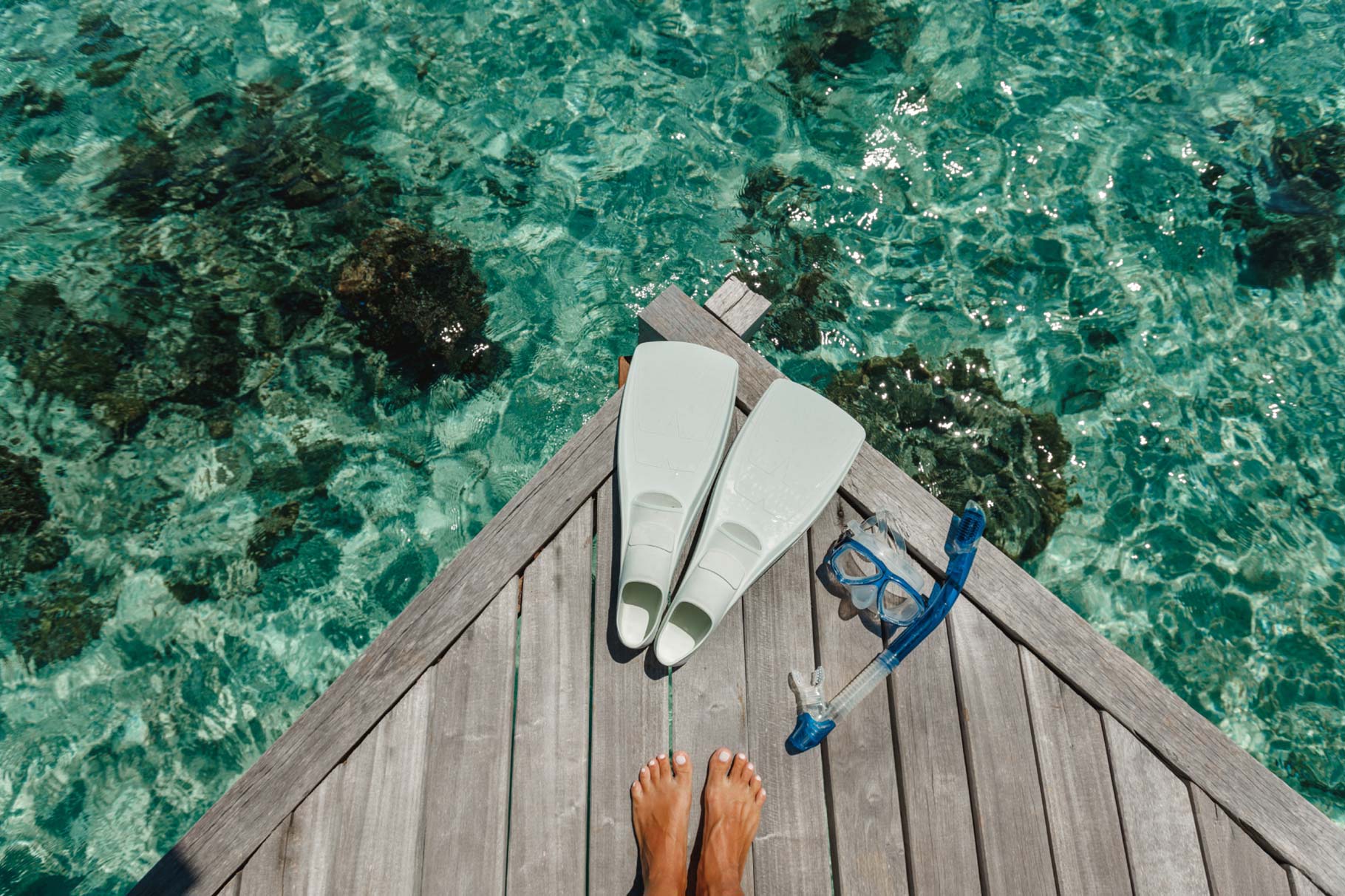 Aerial of feet and snorkel equipment on a deck